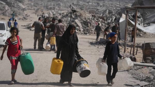 فلسطينيون يحملون عبوات لتعبئتها بالمياه من شاحنة وسط الدمار في غزة (ا ب)