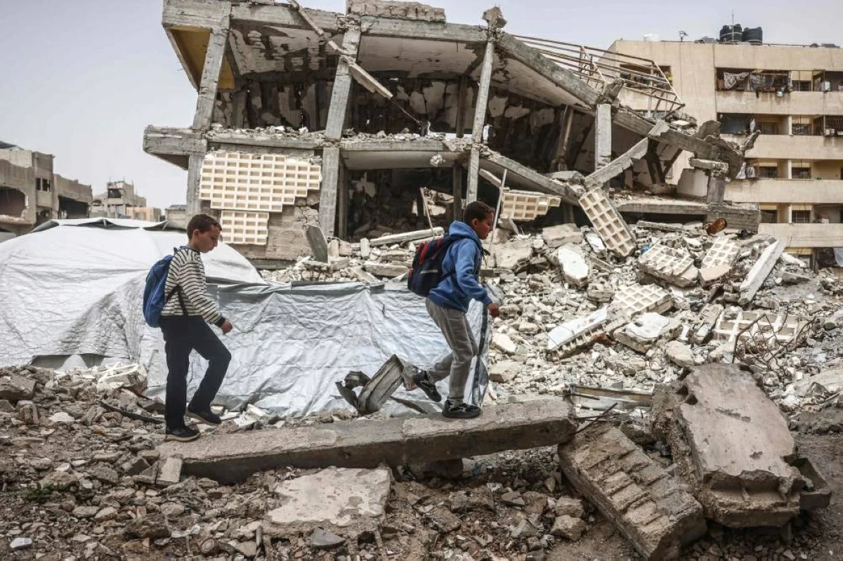 أطفال يسيرون وسط الحطام في قطاع غزة المدمر (أ ف ب)