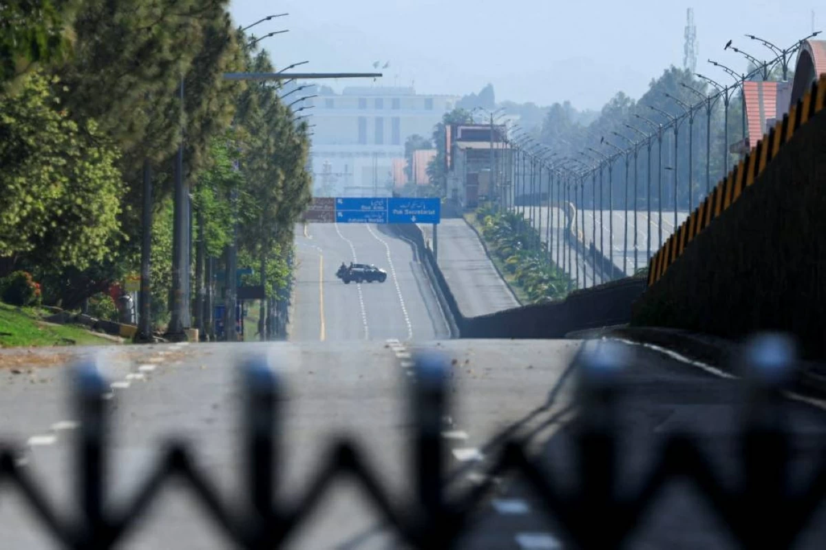 سيارة تجوب الطريق الخالي، وخلفها منزل الرئيس في إسلام آباد (رويترز)