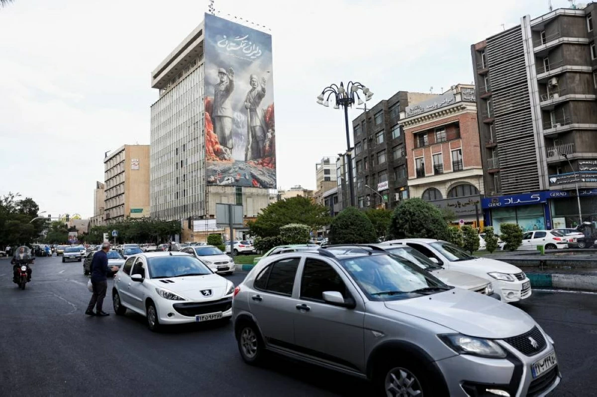 سيارات ومترجلون في شارع وسط طهران في ظل استمرار التوتر الإقليمي (رويترز)