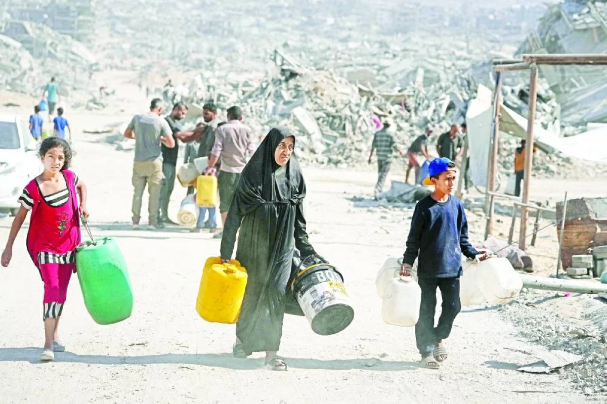 فلسطينيون يحملون عبوات لتعبئتها بالمياه من شاحنة وسط الدمار في غزة (ارشيفية)