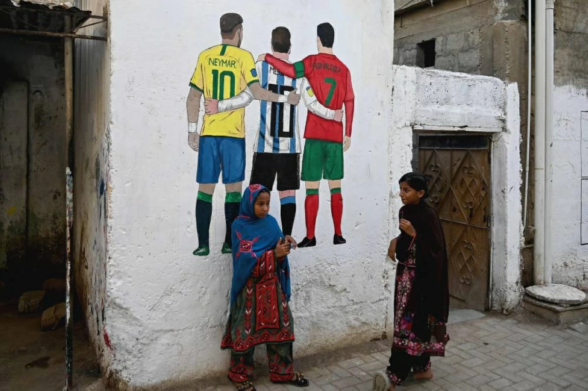 فتاتان تقفان أمام رسم لميسي ورونالدو ونيمار في كراتشي