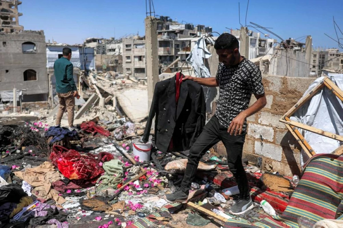 فلسطيني يحمل بدلة زفاف مهند فراونة الذي قتل قبل ساعات من زفافه أمس السبت (أ.ف.ب)
