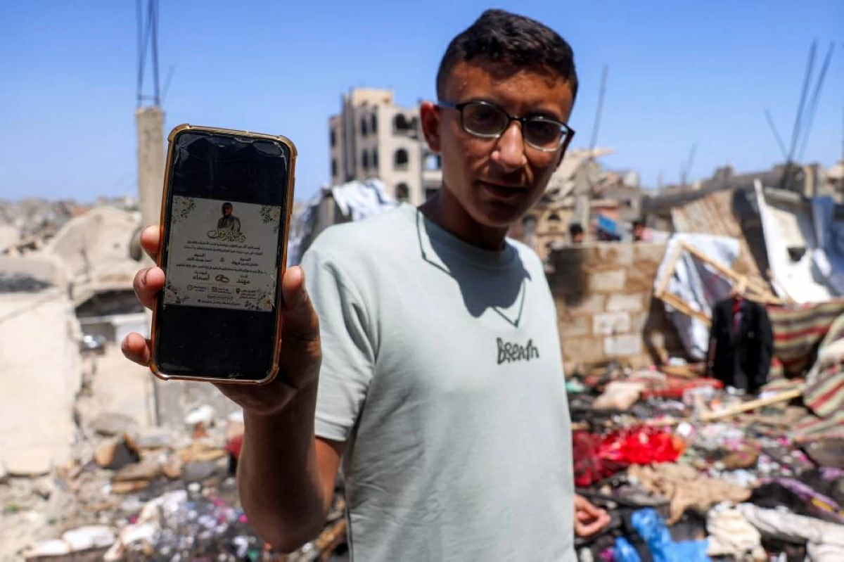  فلسطيني يعرض الدعوة التي وجهها مهند فراونة لزفافه ولكنه قتل في غارة اسرائيلية قبل ساعات من الموعد السعيد (أ.ف.ب)