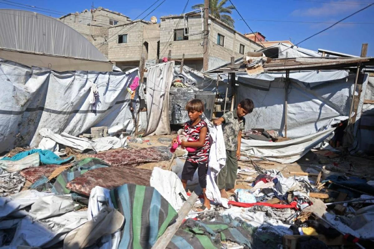 طفلان في موقع خيمة كانت تؤوي نازحين في خان يونس استهدفتها غارة إسرائيلية (أ.ف.ب)