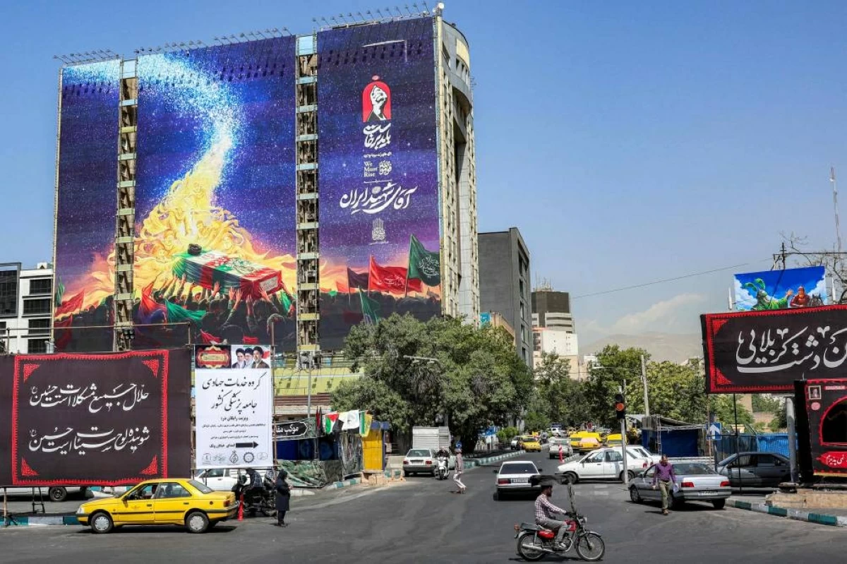 عربات تمر قرب جدارية معروضة على واجهة مبنى في ساحة «فاناك» بطهران (أ ف ب)