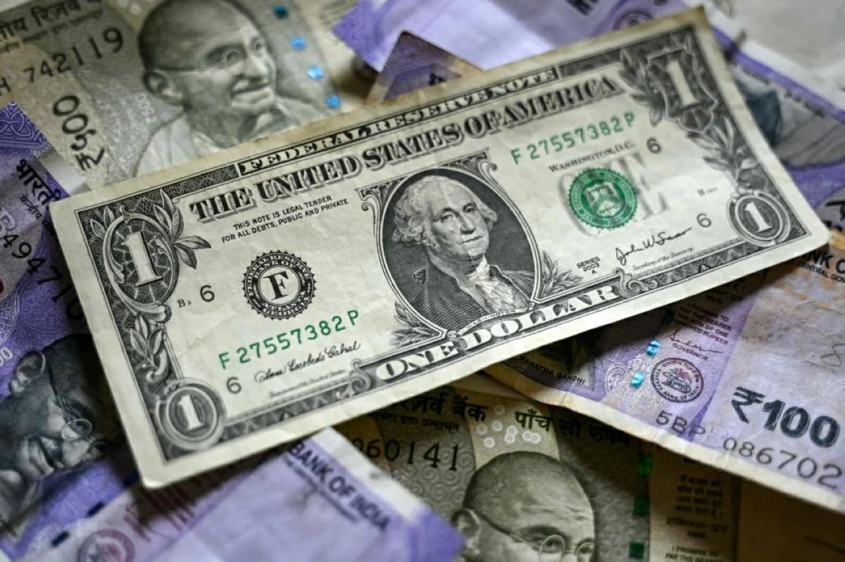 ورقة نقدية من فئة الدولار الأمريكي موضوعة فوق أوراق نقدية من فئة الروبية الهندية في بنغالورو  (أ ف ب)