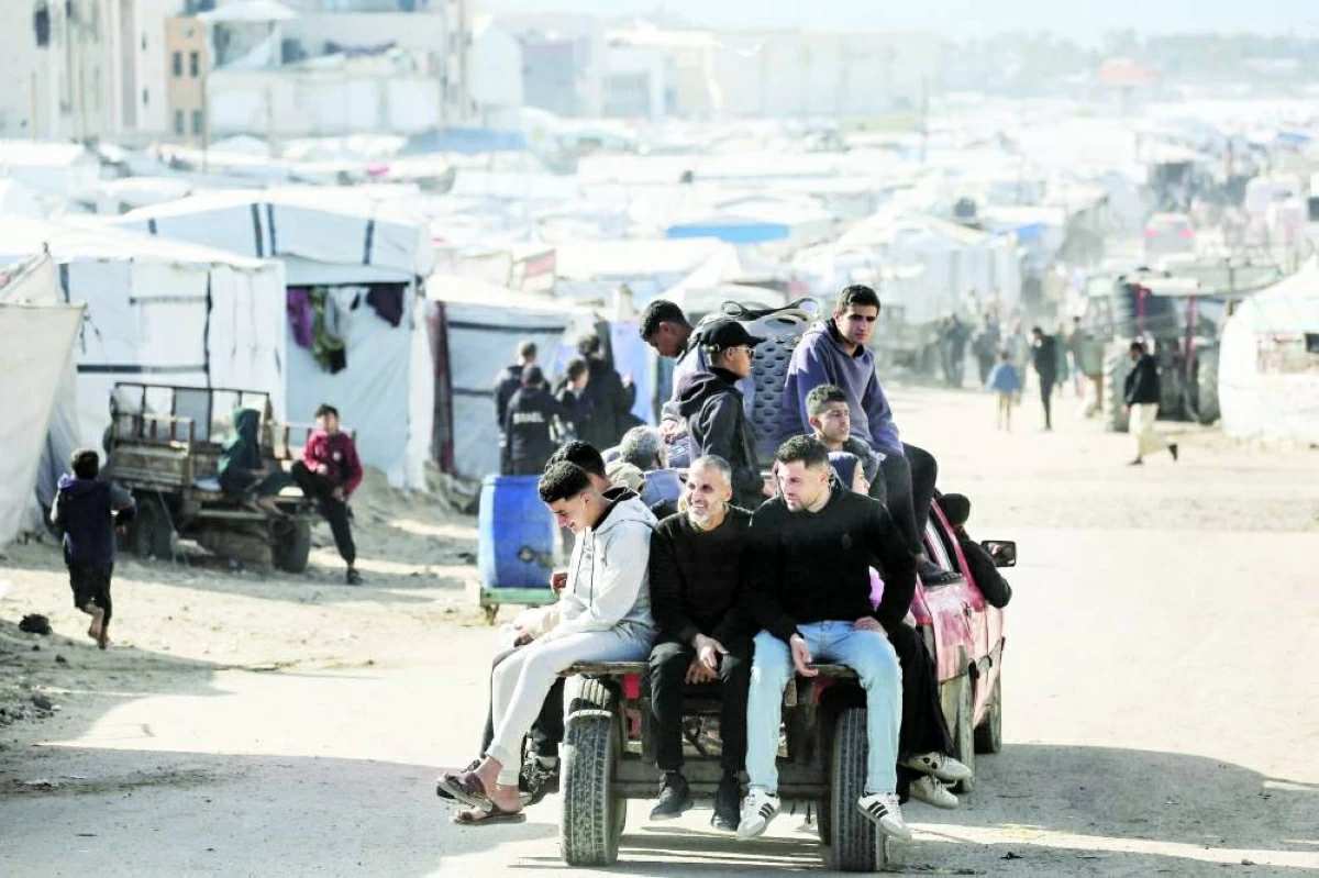 (ا ف ب) فلسطينيون يستقلون شاحنة صغيرة بين خيام النازحين في غزة