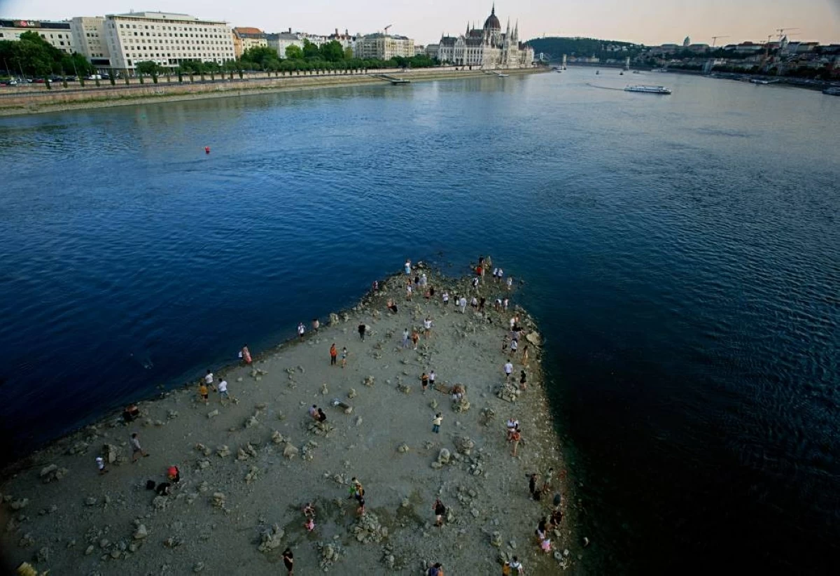 People walk on a sandbar underneath the Danube's Margareth Bridge in downtown Budapest, Hungary, Wednesday Aug. 5, 2026, as the river, which runs through 10 European countries, has receded never-before-seen low water levels. (AP Photo/Bela Szandelszky)
