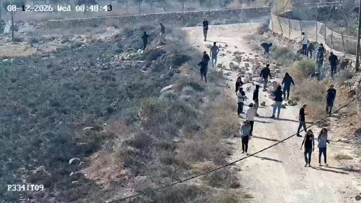 مستوطنون يلقون الحجارة على الطريق في بلدة قصرة شمالي الضفة الغربية (رويترز)