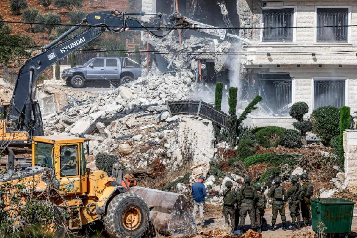 (أ ف ب) جنود إسرائيليون في حراسة جرافات تقوم بهدم مبنى فلسطيني في قلنديا