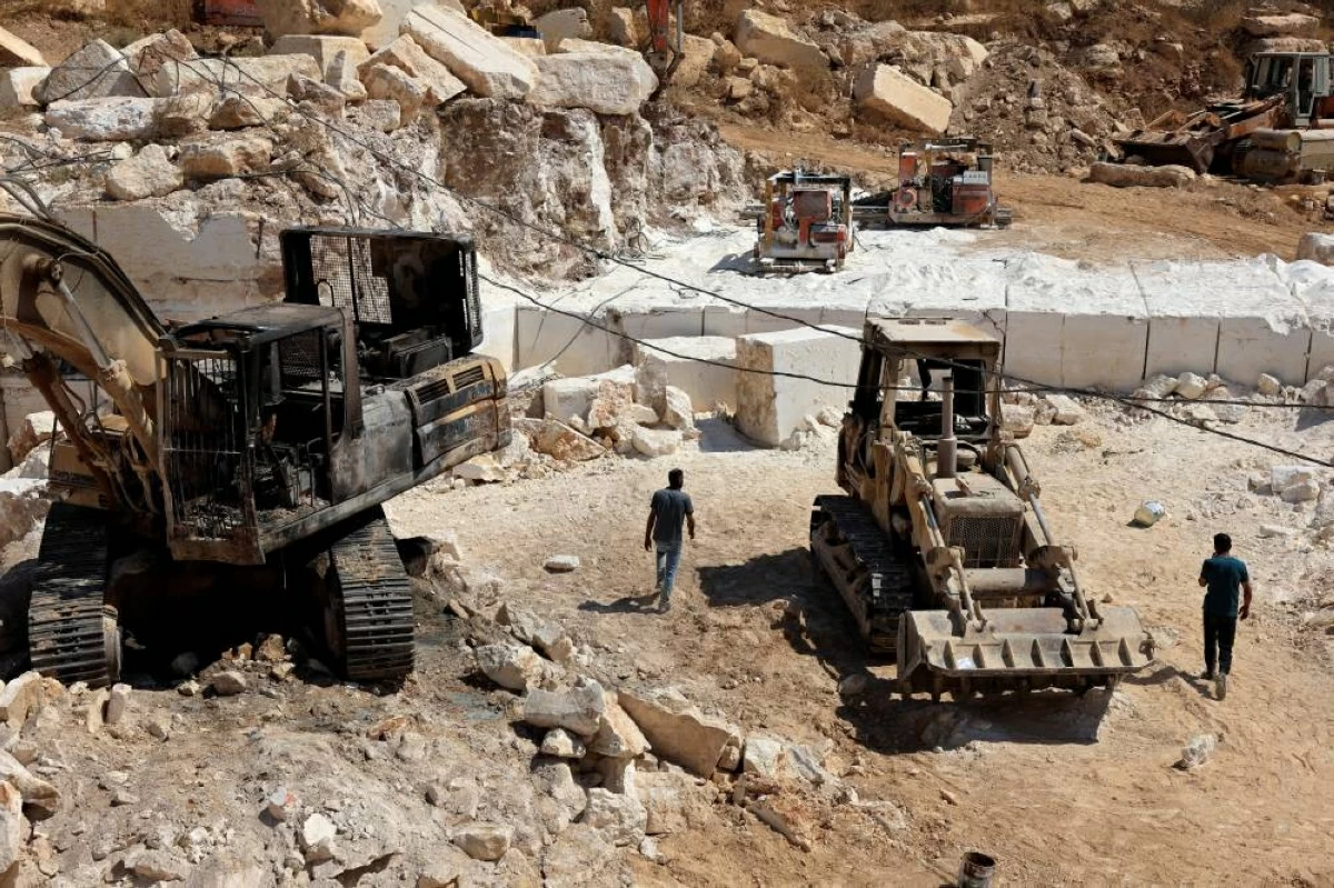 (رويترز) فلسطينيون يتفقدون آلات محجر  أضرم مستوطنون النار فيها  قرب الخليل