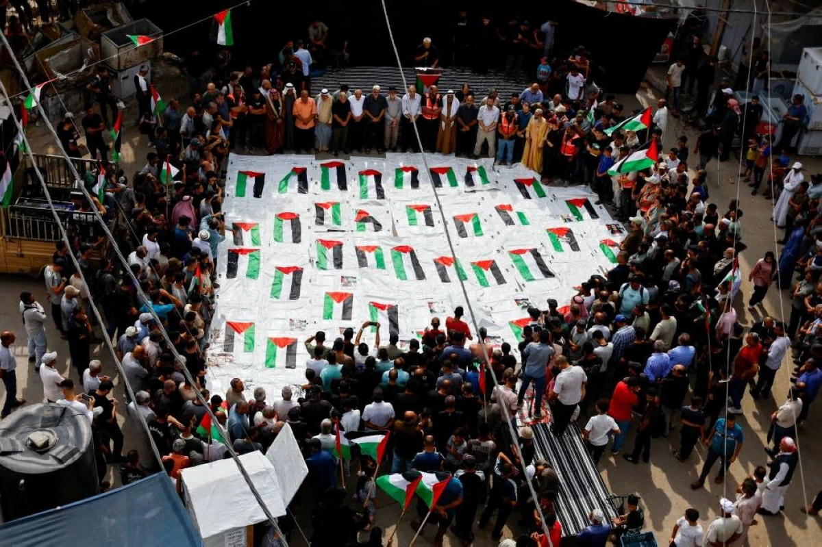 فلسطينيون أثناء تشييع  عشرات الجثامين تم انتشالها من تحت الأنقاض في النصيرات (رويترز)