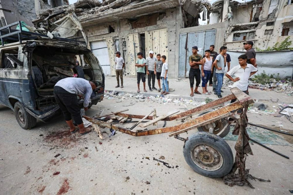 فلسطينيون يتفقدون الأضرار الناجمة عن غارة إسرائيلية استهدفت حافلة صغيرة في حي تل الهوى بمدينة غزة