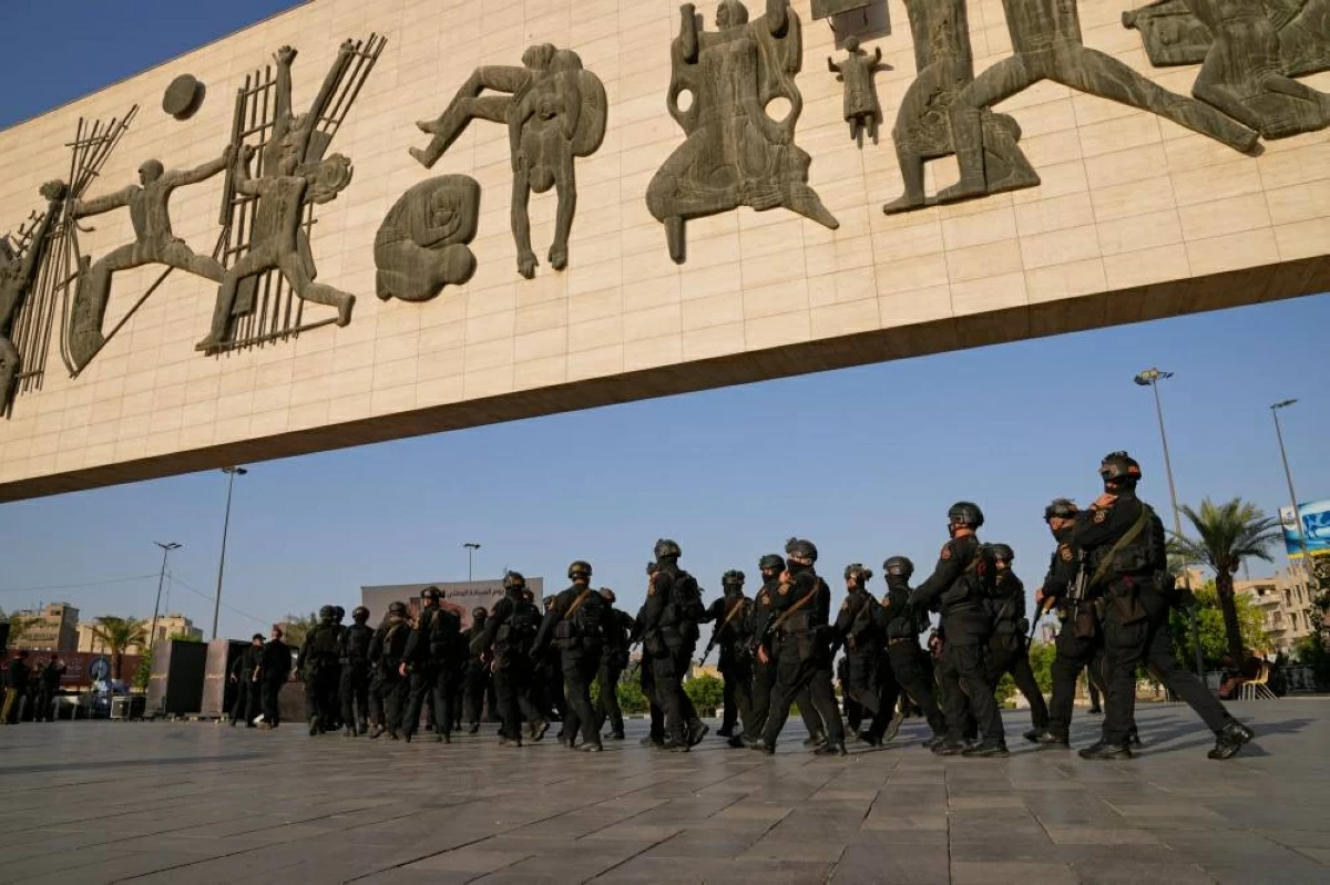 قوات من «الحشد الشعبي» تنتشر في ميدان التحرير وسط بغداد وفي الإطار رئيس الوزراء علي فالح الزيدي (أ.ف.ب)