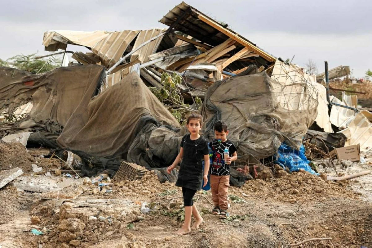 أطفال يمرون بين أنقاض أحد المباني المدمرة بالنقب 
(ا ف ب)