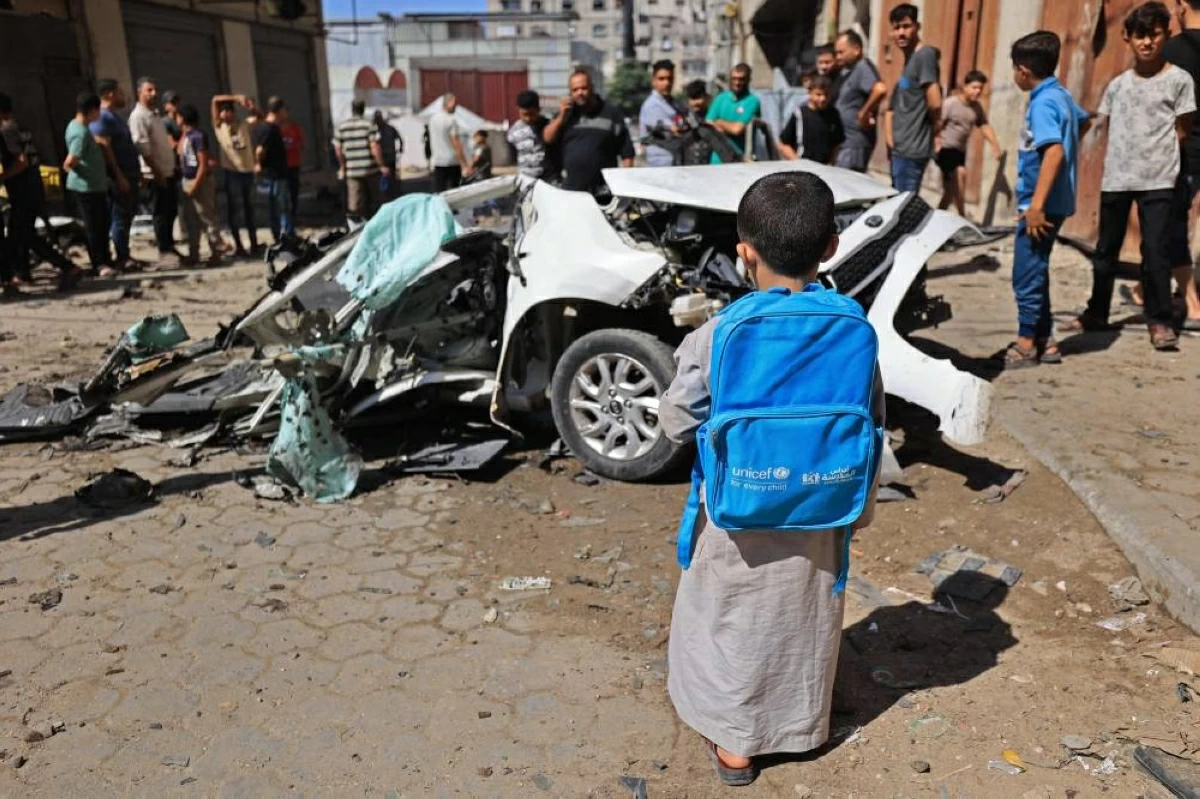 طفل ينظر إلى حطام سيارة استهدفتها غارة إسرائيلية في حي التفاح بمدينة غزة 
(ا ف ب)