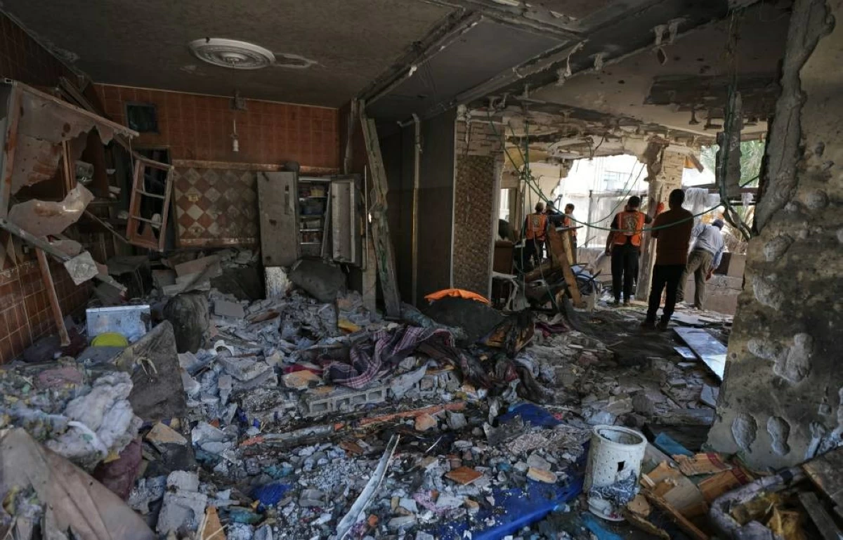 فلسطينيون يتفقدون الأضرار بمبنى سكني تعرض لغارة إسرائيلية في مدينة غزة (ا ب)