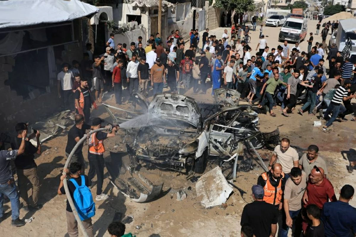 فلسطينيون يتجمعون حول حطام مركبة بعد تعرضها لغارة إسرائيلية في غزة (رويترز)