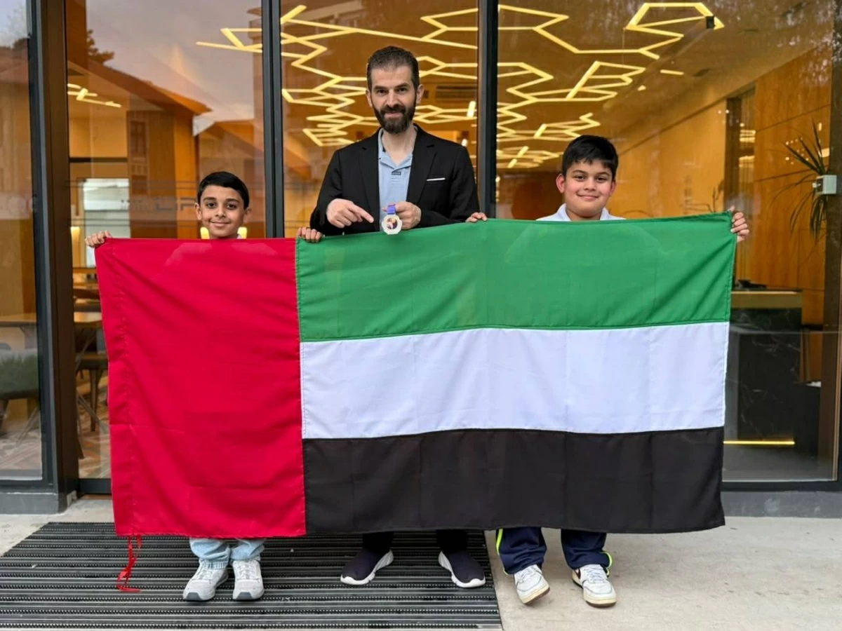 مدرب الفريق والطالبان يرفعون علم الإمارات احتفالاً بالإنجاز