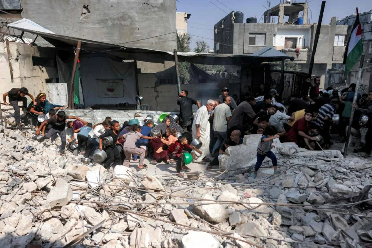 فلسطينيون يصطفون للحصول على وجبات من مطبخ خيري في مخيم جباليا (أ ف ب)
