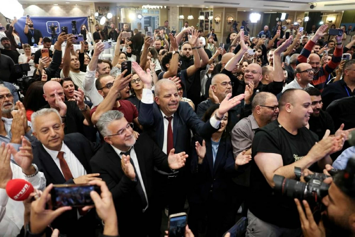 Yousef Jabareen, leader of Israel's Arab-led Joint List political alliance, (Centre-L) and other members of the Arab-led Joint List political alliance, cheer at the alliance's campaign headquarters in the northern Israeli city of Nazareth  on October 27, 2026, as the first exit polls are announced on television during Israel's legislative election. Israeli voters on October 27 gave a narrow edge to opposition parties over Prime Minister Benjamin Netanyahu, initial projections showed, after decades-high turnout in the country's first election since the trauma of the October 7, 2023 attacks. (Photo by AHMAD GHARABLI / AFP)