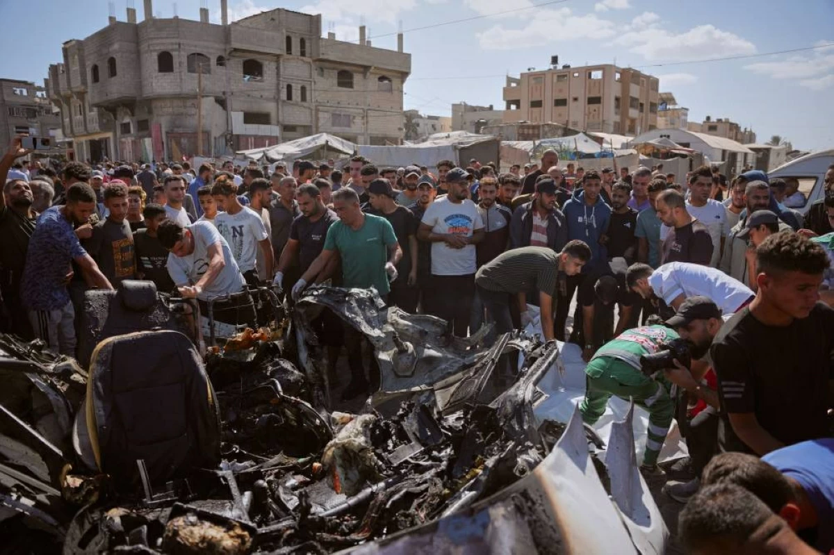 (ا ب) فلسطينيون يتفقدون حطام سيارة دمرتها غارة  إسرائيلية في مخيم المغازي