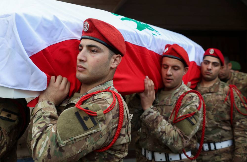جنود من الجيش اللبناني يحملون نعش الرقيب عبد الكريم المقداد الذي قُتل بقصف إسرائيلي (رويترز)