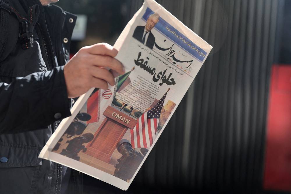 إيراني يحمل صحيفة تحتوي على صورة لعلمي إيران والولايات المتحدة في شارع بطهران( رويترز.)