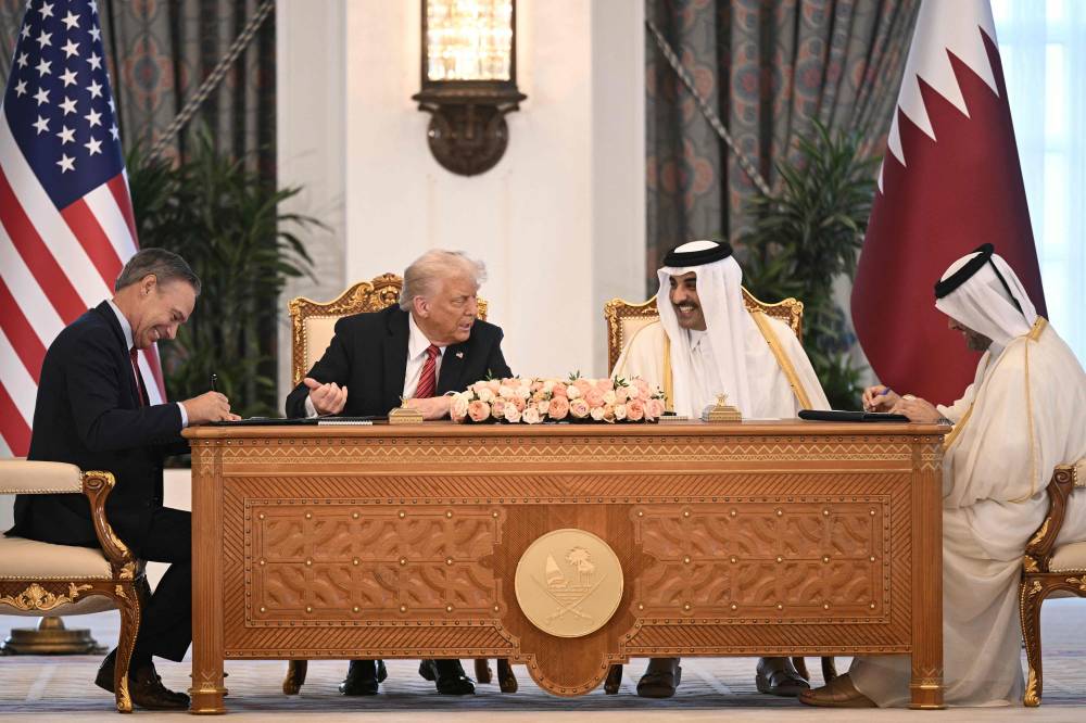 كيلي أورتبرغ ودونالد ترامب وأمير قطر خلال حفل توقيع الاتفاقية في القصر الملكي بالدوحة (أ ف ب)