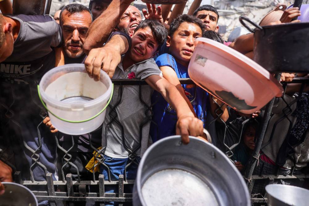 فلسطينيون يتدافعون للحصول على حصة من الطعام المطبوخ من مطبخ خيري في جباليا (أ ف ب)