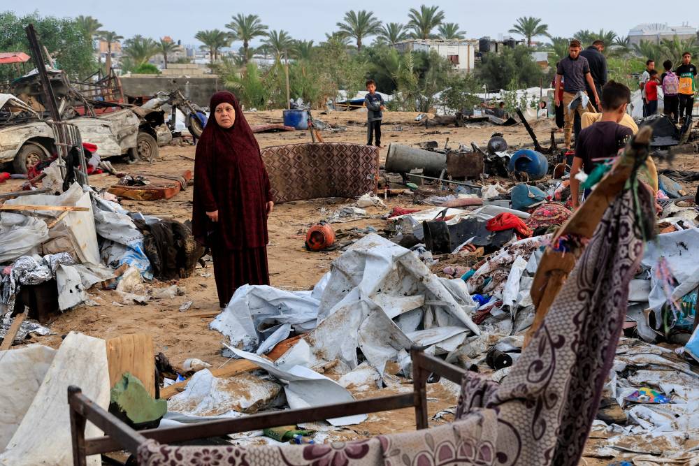 (رويترز) فلسطينيون يتفقدون الأضرار في موقع غارة إسرائيلية على مخيم للنازحين في خان يونس