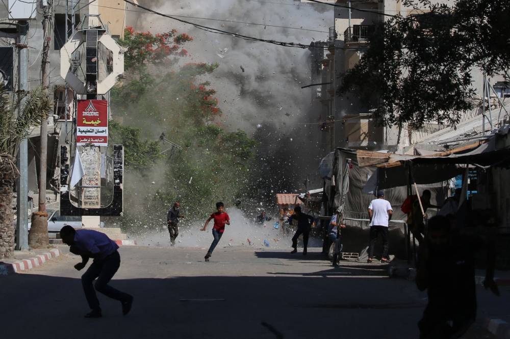فلسطينيون يسارعون للاحتماء بينما خلال غارة إسرائيلية على مخيم البريج (ا ف ب)