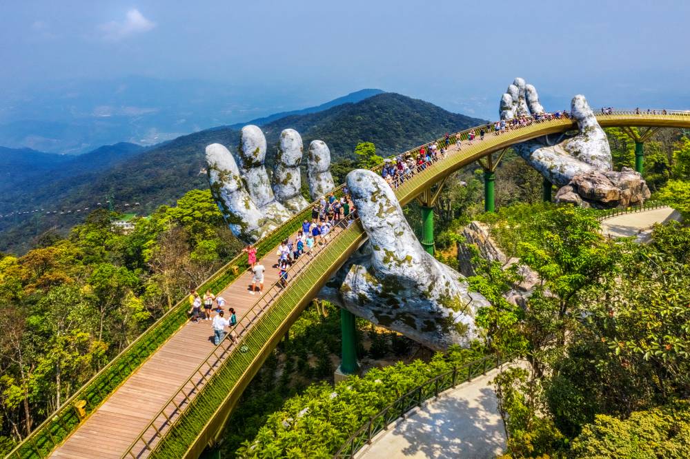 Young traveler Couple Walking on the Golden Bridge in Bana hills, enjoying the morning , Danang Vietnam