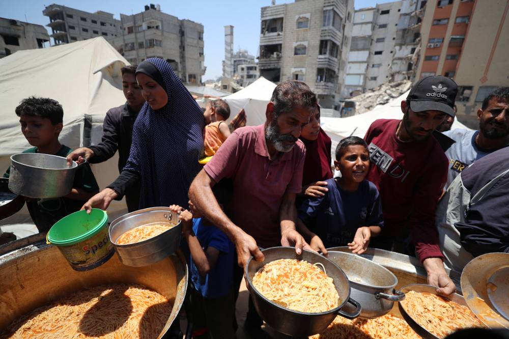 فلسطينيون يتدافعون للحصول على طعام في مطبخ خيري في غزة(رويترز)