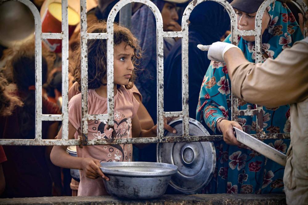 طفلة فلسطينية تنتظر أمام مطبخ توزيع طعام في منطقة المواصي برفح (أ ف ب)