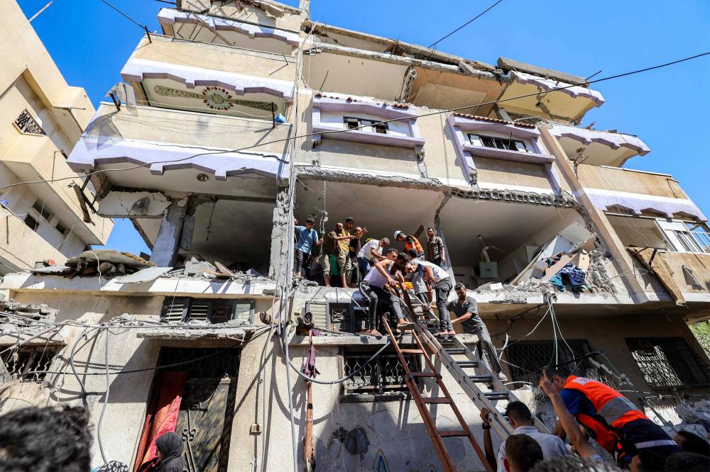 فلسطينيون يساعدون في إجلاء امرأة على نقالة من مبنى تعرض لقصف إسرائيلي في النصيرات (ا ف ب)