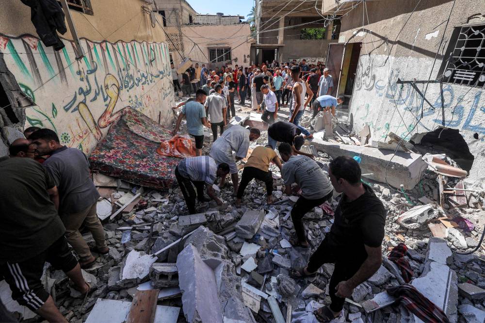 فلسطينيون يبحثون بين أنقاض مبنى تعرض للقصف الإسرائيلي في مخيم النصيرات (ا ف ب)