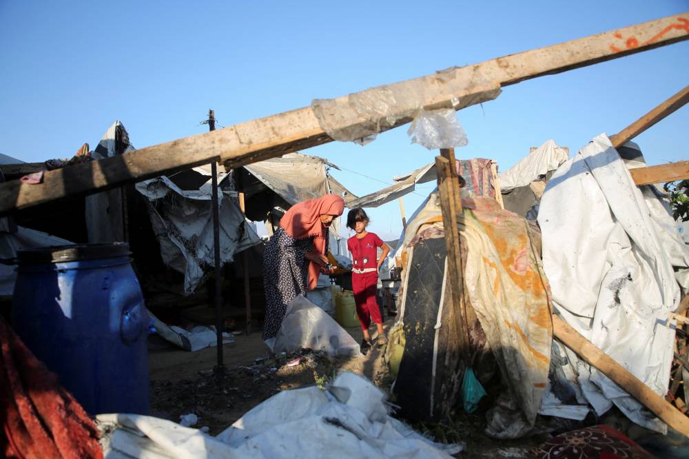 أم وابنتها تتفقدان الأضرار في خيمة للنازحين استهدفتها غارة إسرائيلية في خان يونس (رويترز)