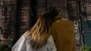 يقفان والحزن ثالثهما أمام المباني المحترقة