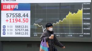 امرأة تمر أمام شاشة لقراءة مؤشر الأسهم اليابانية نيكاي