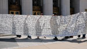 آباءٌ خارج المحكمة يرفعون لافتةً تحمل أسماء يقولون إنها لأبنائهم الذين فقدوهم بسبب وسائل التواصل الاجتماعي (رويترز)