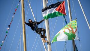 ناشط يتسلق سارية قارب يحمل العلم الفلسطيني في ميناء مرسيليا جنوب فرنسا، (في 4 أبريل 2026 / أ.ف.ب)