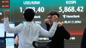 يتجاذبان أطراف الحديث أمام شاشة تعرض مؤشر أسعار الأسهم الكوري كوسبي وصرف العملات الأجنبية (أ.ب)