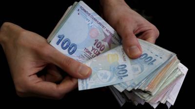 تاجر يحصي الأوراق النقدية بالليرة التركية في البازار الكبير بإسطنبول (رويترز)