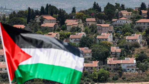 (ا ف ب) مستوطنة إسرائيلية تظهر خلف علم فلسطيني مرفوع خلال جنازة الطفل التميمي