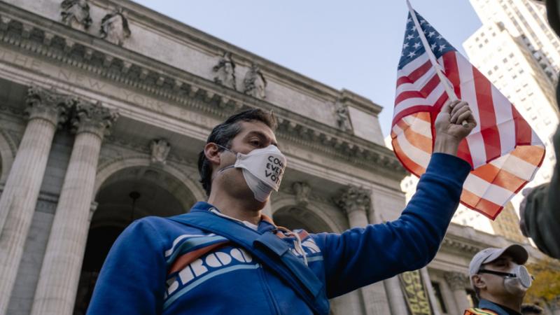 متظاهر يرتدي القناع ويحمل العلم الأمريكي في مظاهرة خلال الانتخابات الرئاسية لعام 2020 في نيويورك 