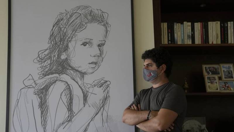 والد ألكسندرا نجار يقف بجانب رسمة لابنته (أ.ب)
