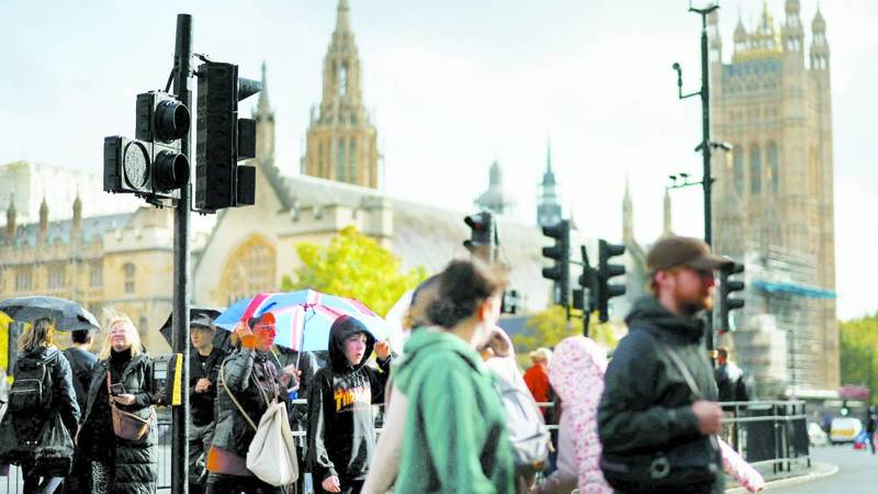 اشخاص يمرون بمحاذاة مبنى البرلمان البريطاني في لندن (رويترز)