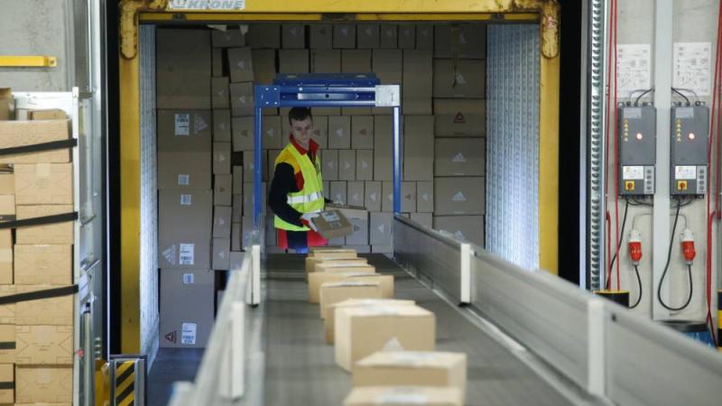 موظف يضع الطرود على الحزام الناقل بمركز "دي اتش أل" في بوخوم، ألمانيا (رويترز)